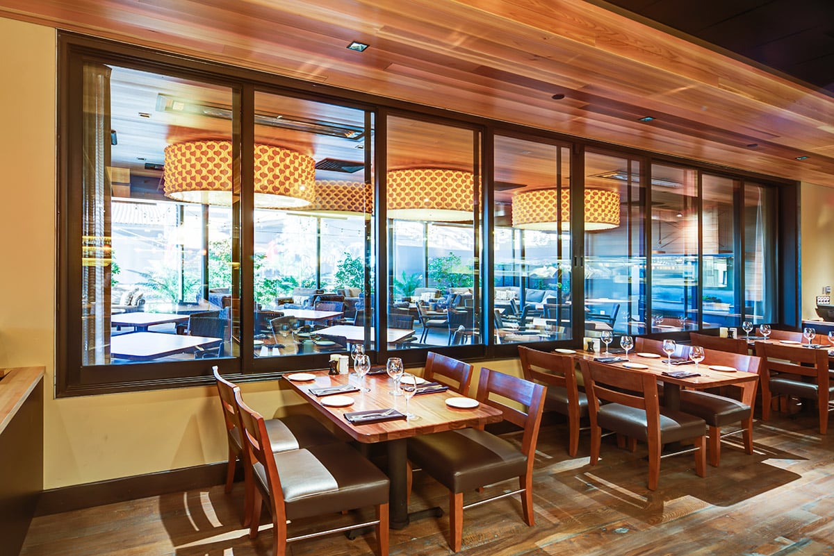 A view of multi-slide windows connecting two separate dining spaces.