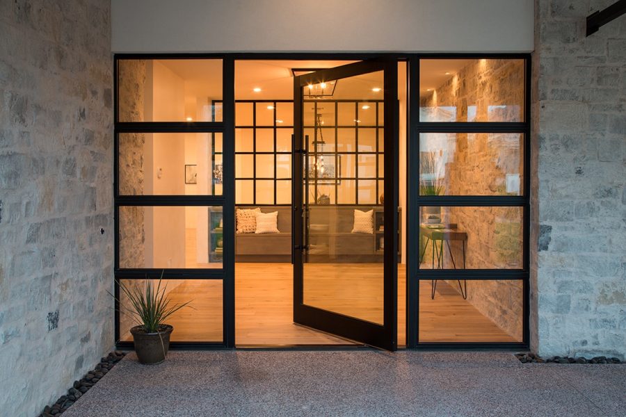 An extra wide pivot door is flanked by two gridded windows.