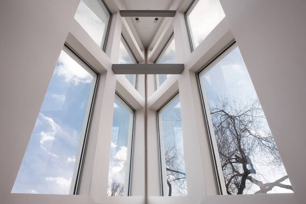 Windows on all three floors of the home are visible from the angled, triangular interior atrium.