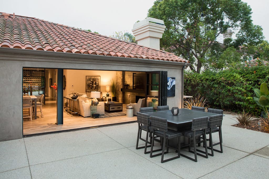 Open Series 9500 Bi-Fold Doors merge the indoor dining area with an outside sitting area.