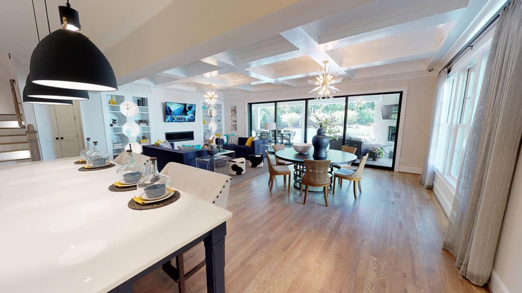 An indoor living and dining room has floor-to-ceiling multi-slide glass doors that lead outside.