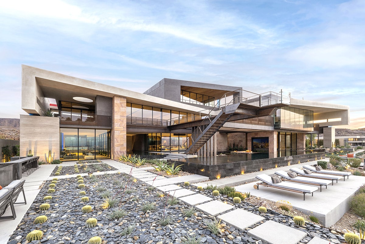 A view from the back of the three-story house with large multi-slide doors overlooking the gravel landscaping in the backyard.