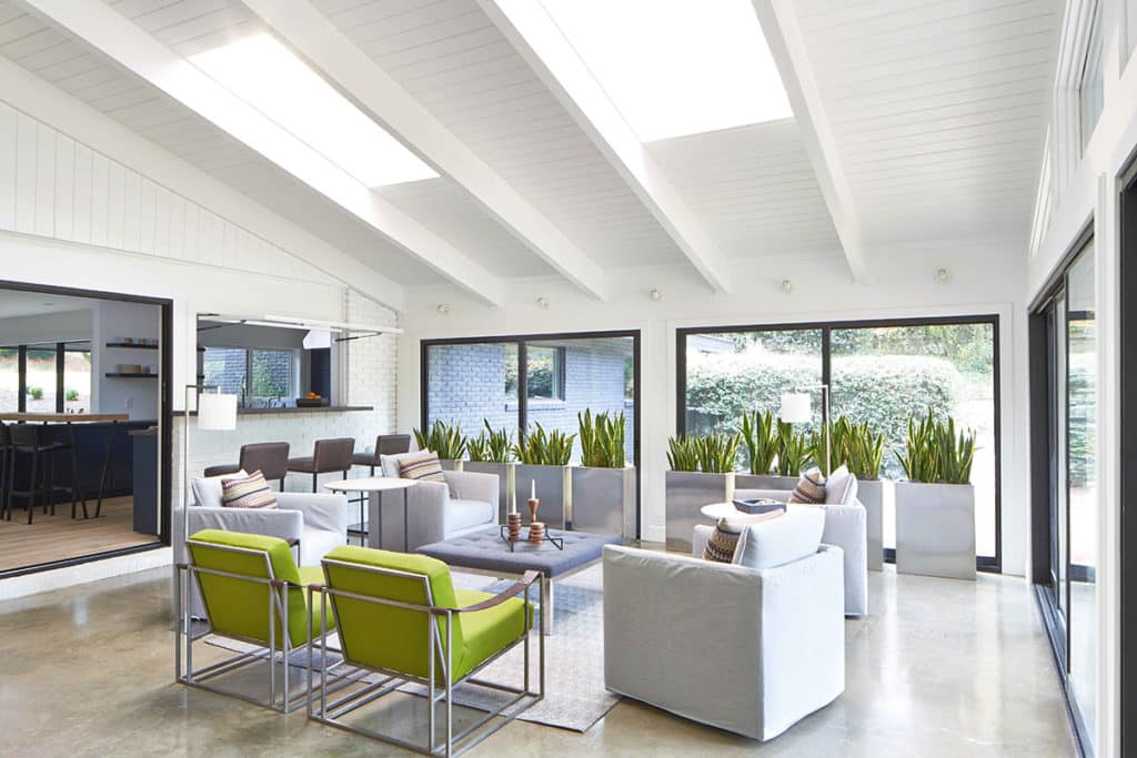 A view of the seating area in the enclosed sunroom surrounded by sliding glass doors.
