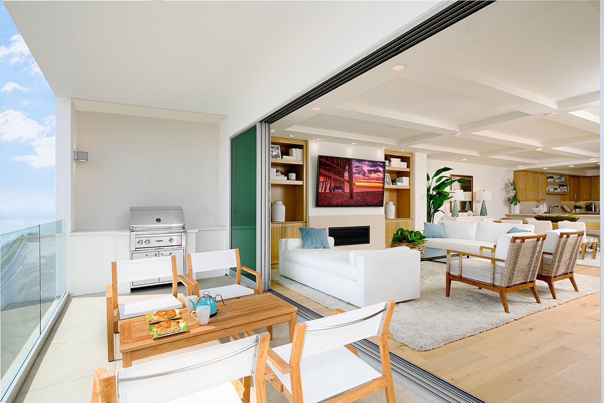 An open multi-slide door connects the patio dining area to the living room