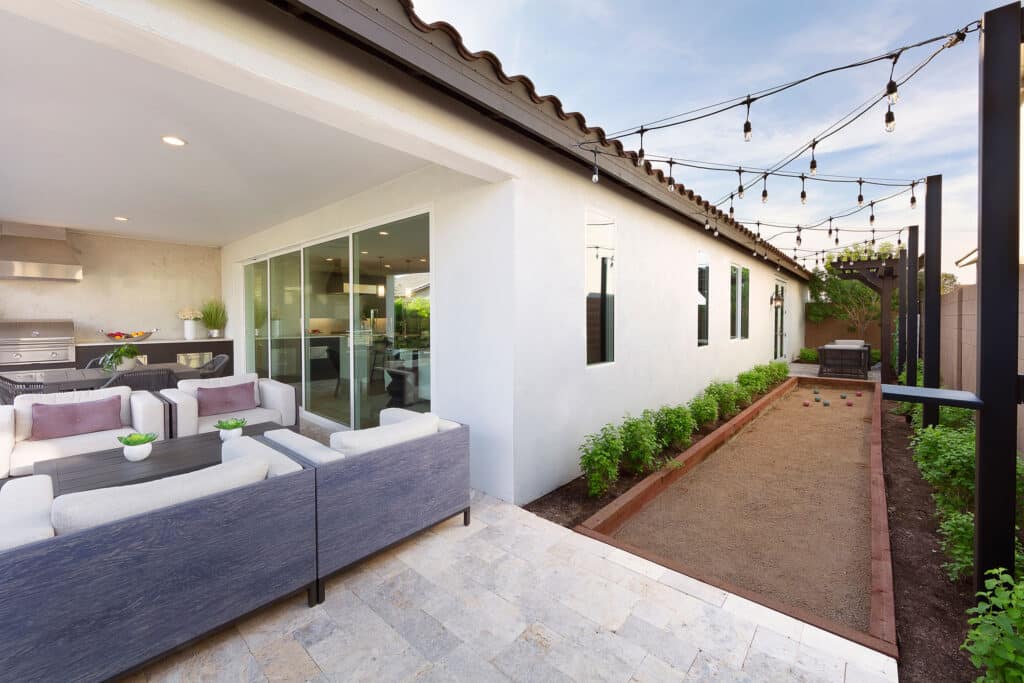 A view of an outdoor living area and bocce ball playing space separated from the indoors by a closed multi-slide glass door.