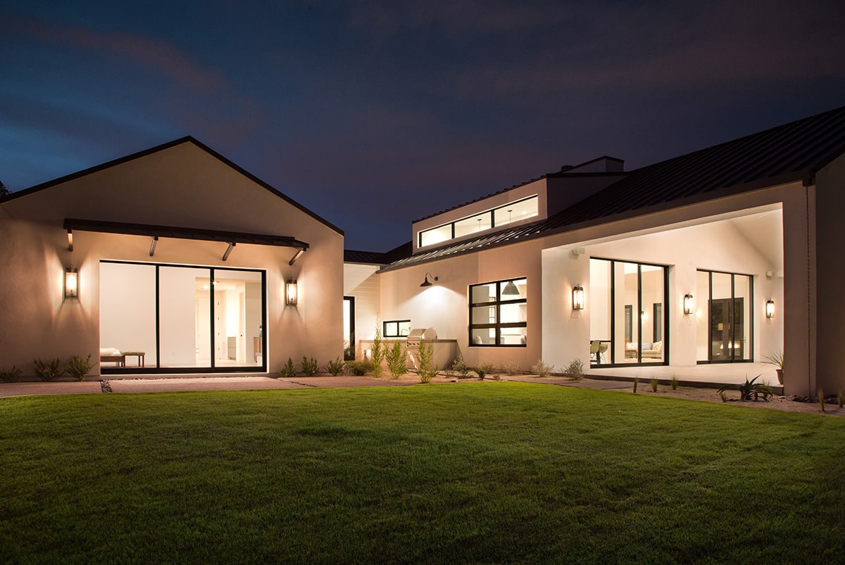 Several multi-slide doors leading to the grassy backyard appear in the Modern Farmhouse in Phoenix.