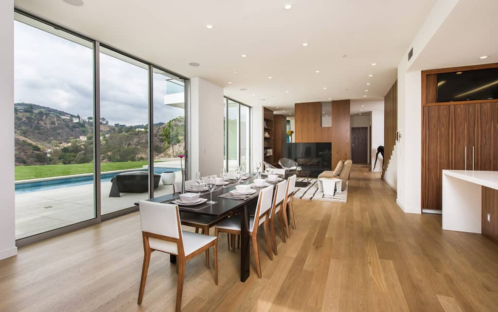 Floor-to-ceiling multi-slide doors connect the great room to the pool and lawn outside.