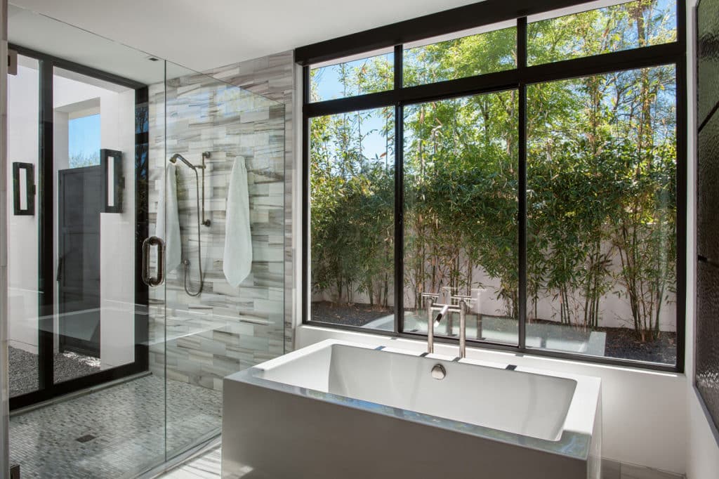 Fixed windows provide views of the yard from behind the bathtub.