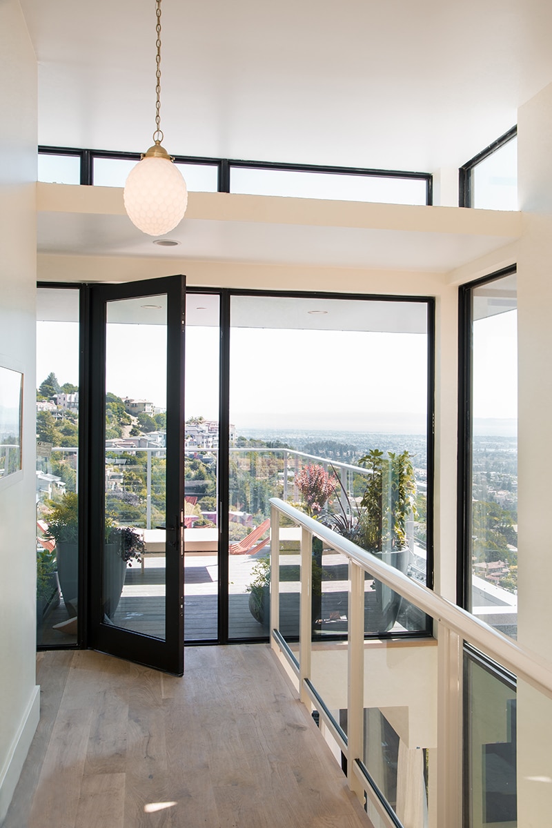 Floor-to-ceiling windows and a hinged door connect to a corner balcony.