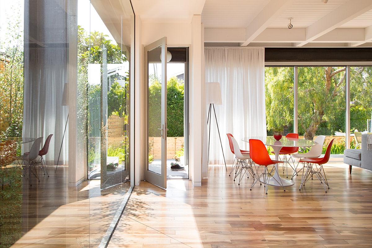 A hinged door opens to the backyard next to walls of glass.