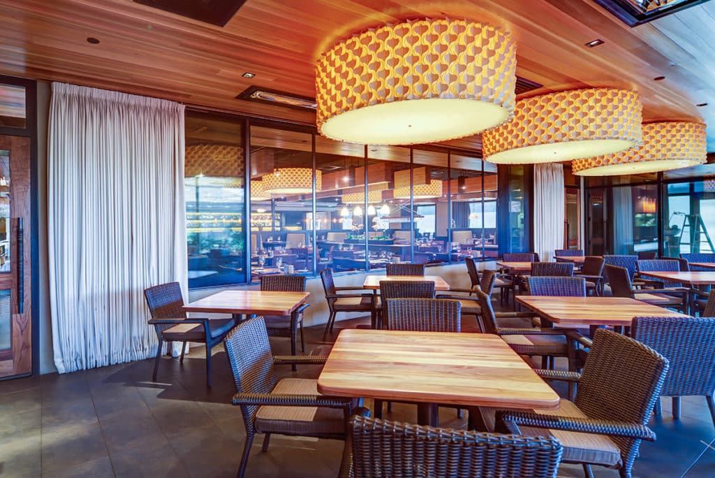 A huge multi-slide window separates the main dining room from an outdoor patio.