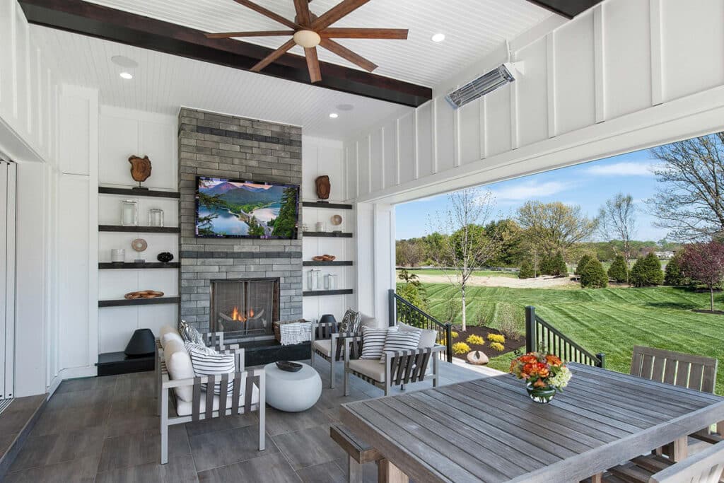 An outdoor seating area is connected to the indoors and colorful backyard by a floor-to-ceiling multi-slide glass door.