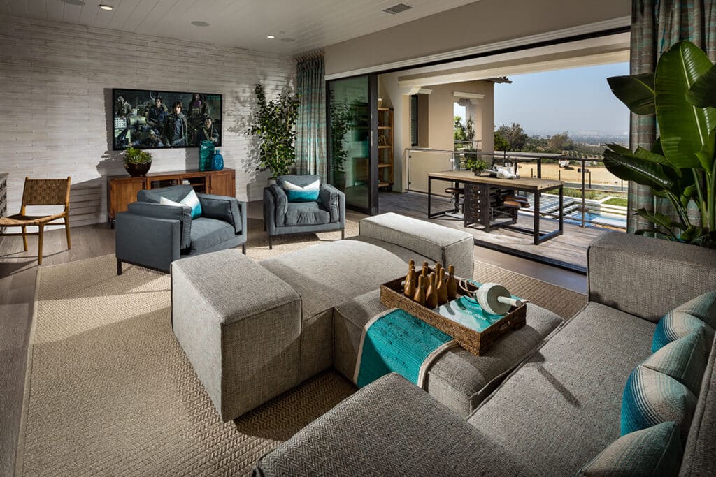 A nautical themed indoor living area is illuminated with natural light from an open multi-slide glass door that leads to the outdoors.