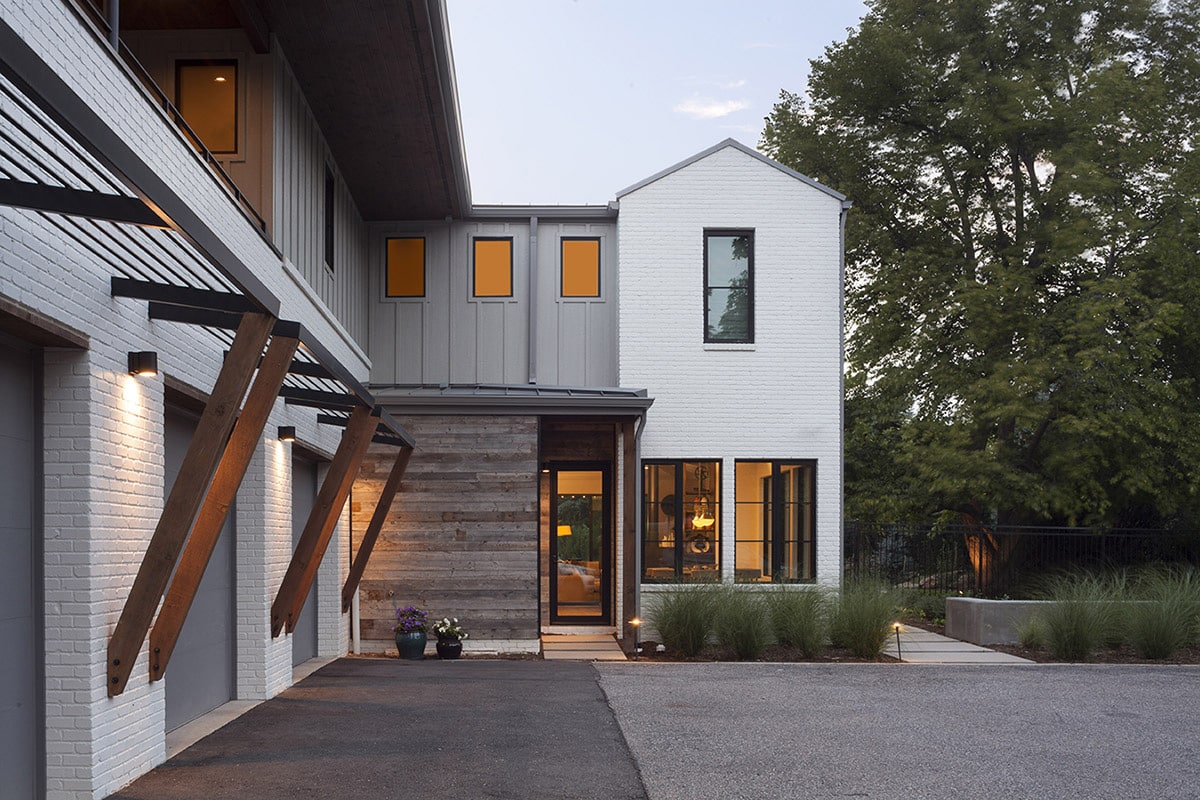 A side view of the modern, Cape Cod-style home featuring a series of fixed windows and a hinged front glass door with narrow profiles.