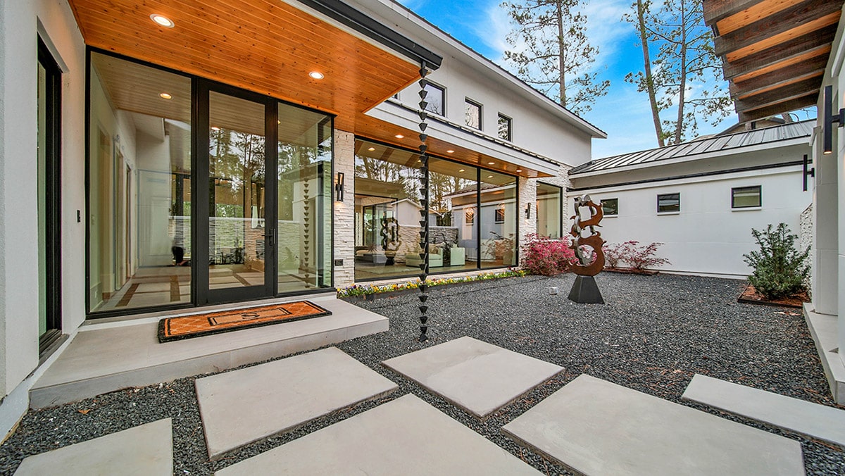 Walls of glass welcome visitors into the home from the front courtyard.