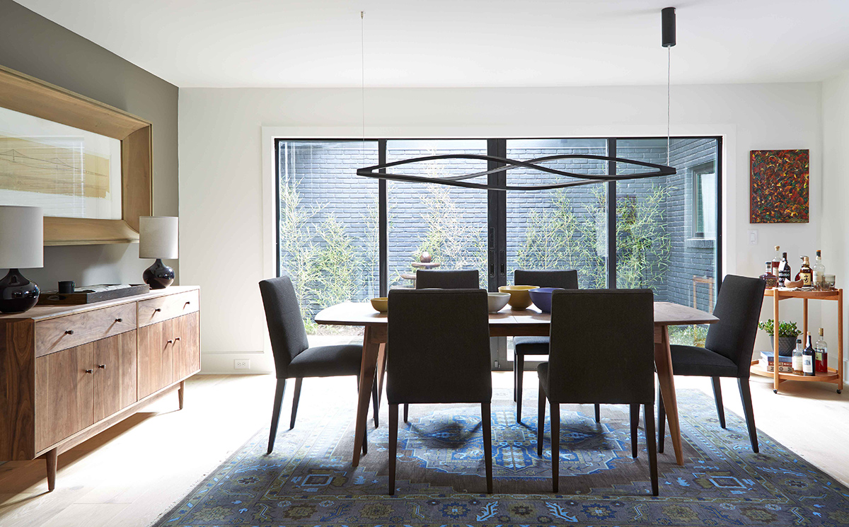 A view of the dining room with a large, bi-parting sliding glass door leading to a courtyard.