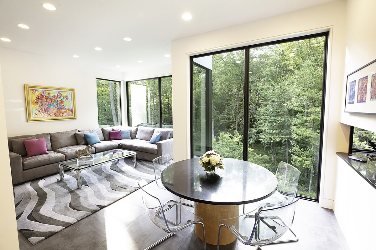 Glass in this sitting and dining area frames the lush green landscape surrounding the Westchester County, New York home.
