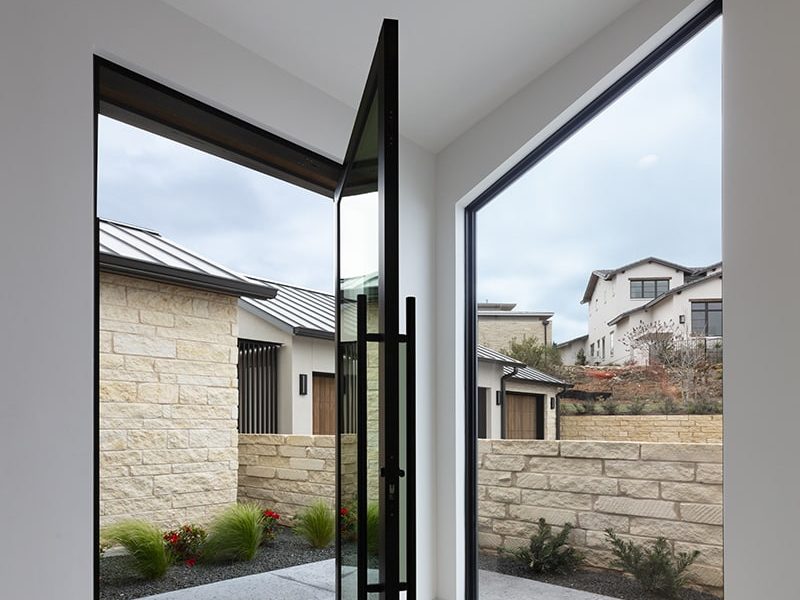 03-PHOTO 22 A glass pivot door sits at a 90-degree angle from a fixed window the same size.