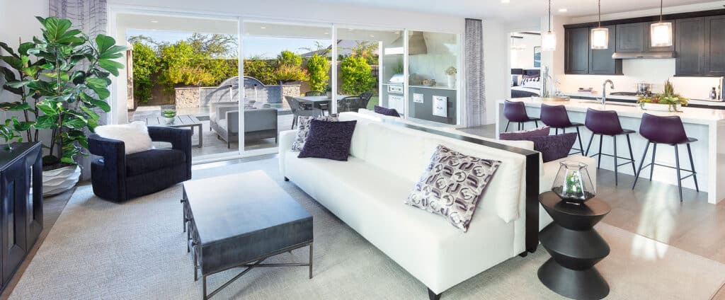A living room is illuminated with natural light through a closed multi-slide glass door that transitions to the backyard.