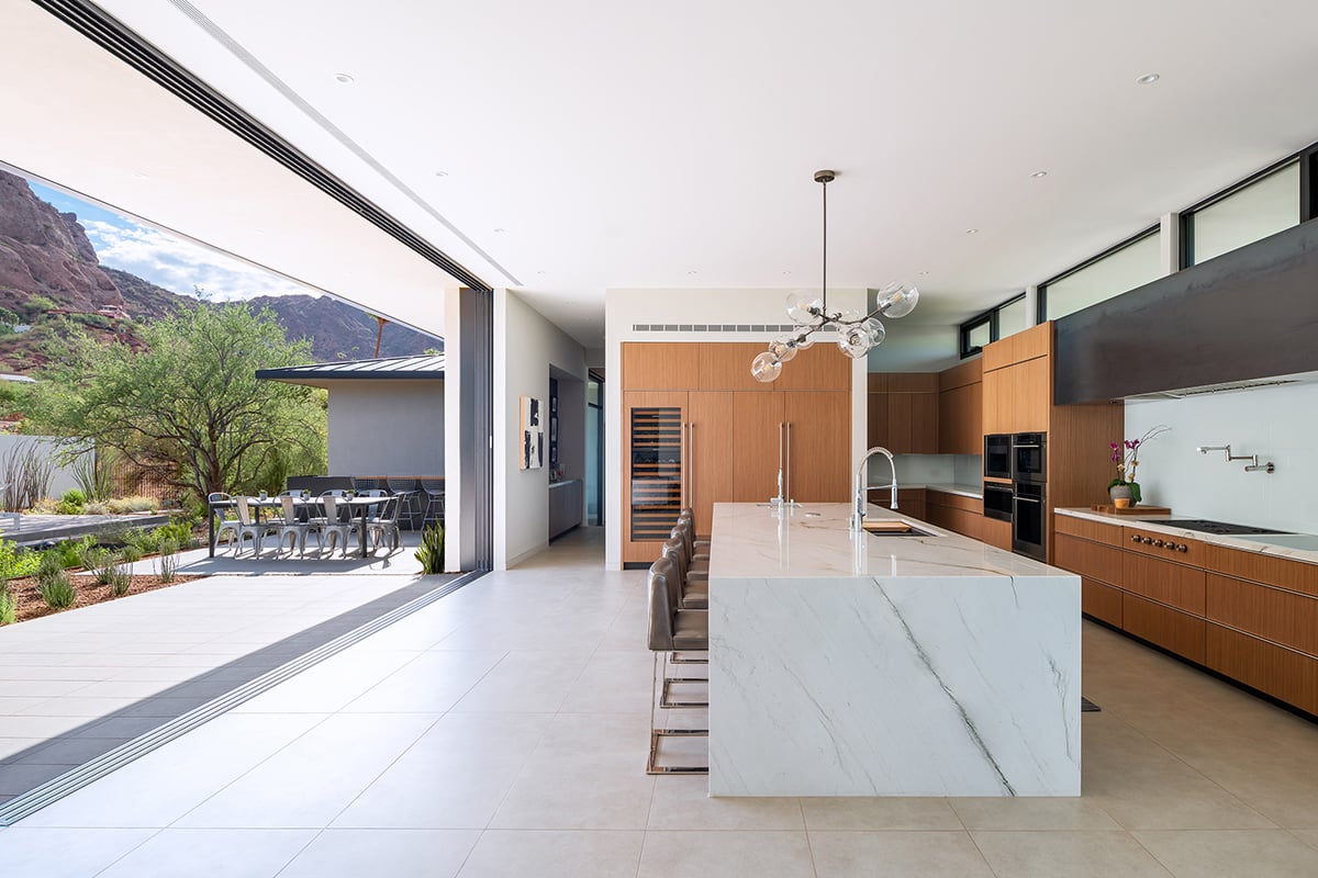 A moving wall of glass opens the kitchen of the home to an outdoor space at the base of Camelback Mountain.