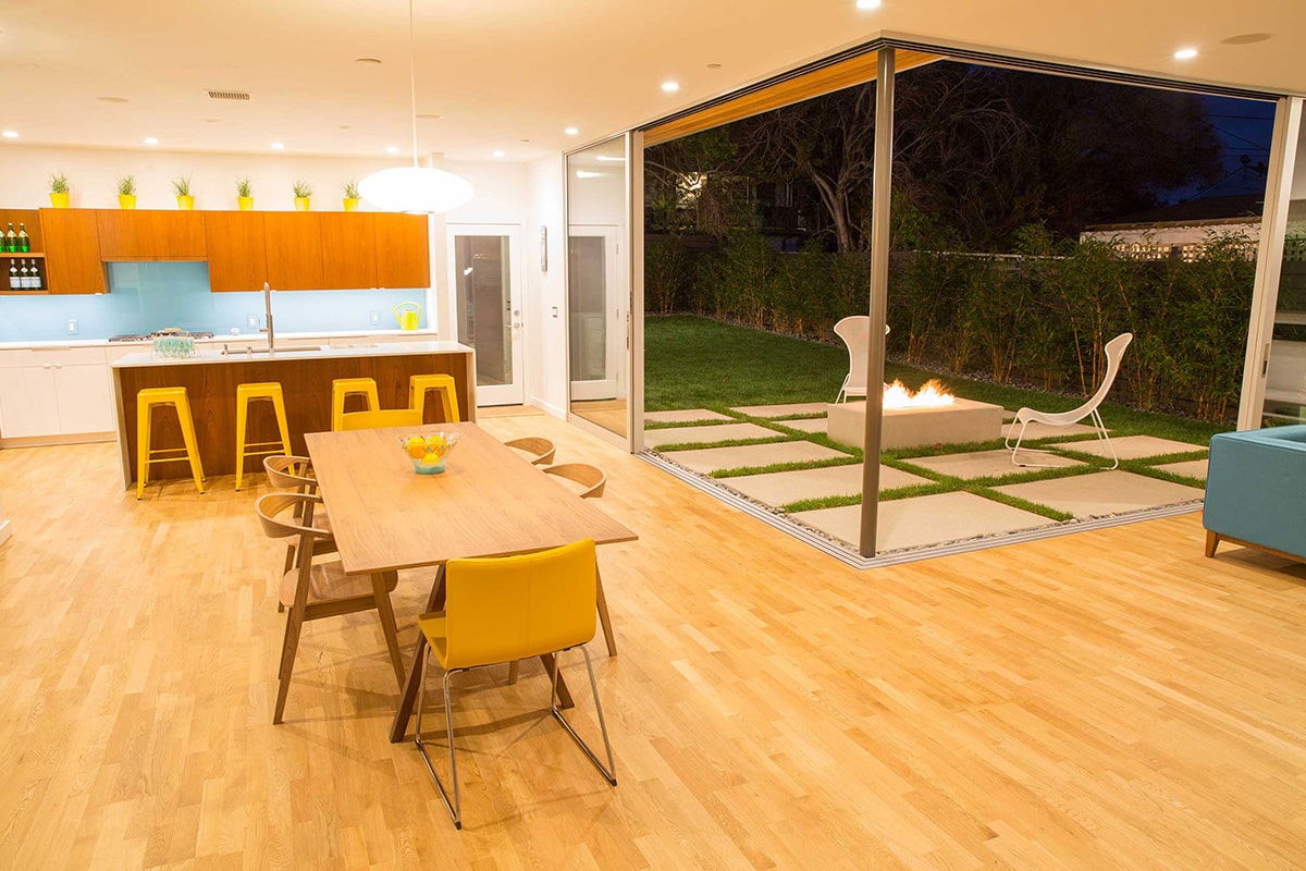 A 90-degree multi-slide door connects the living room, dining room, and kitchen to the grassy backyard with a fireplace.