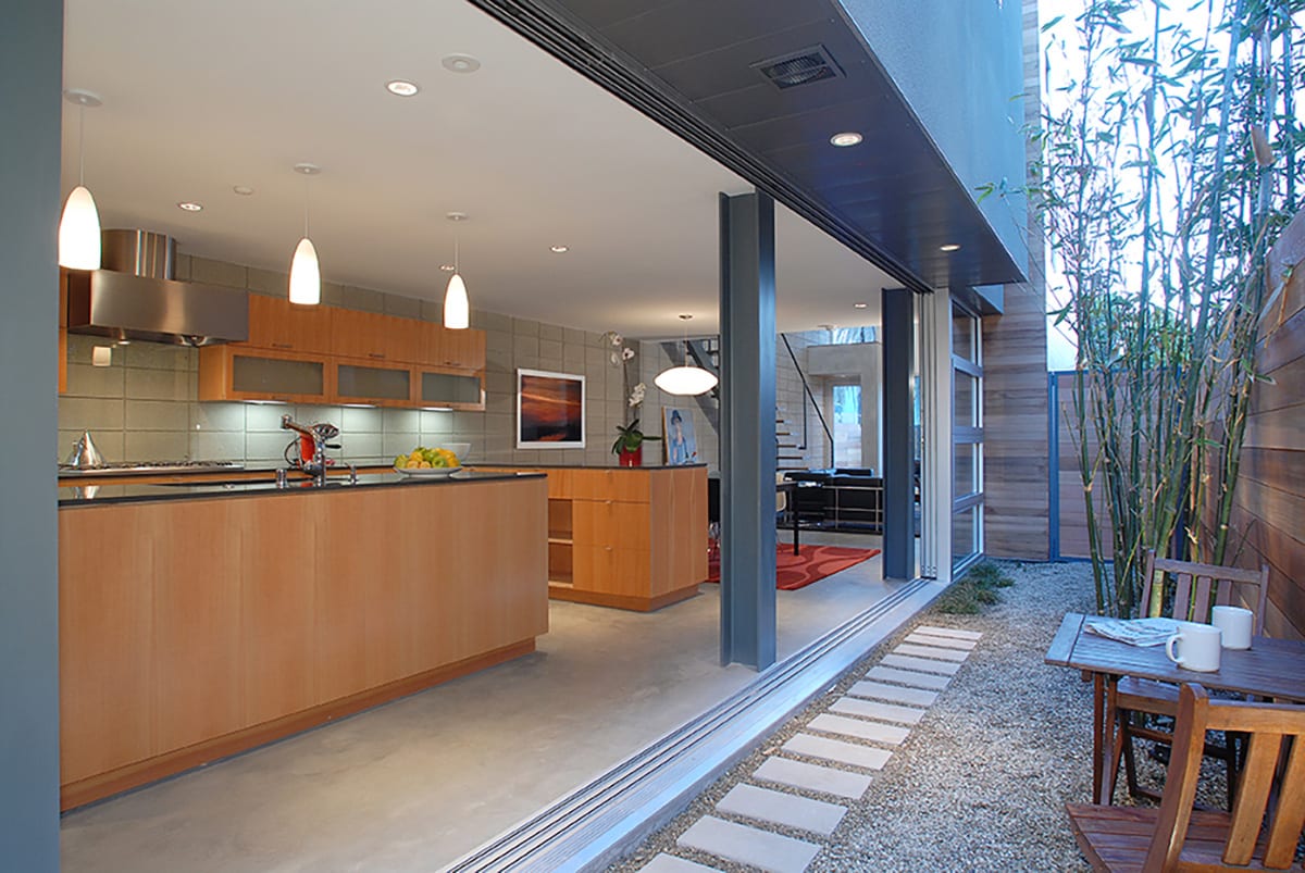 The modern, open kitchen gets even bigger when the massive Series 600 Multi-Slide Door is open, showing off steel beams that reach the ceiling.