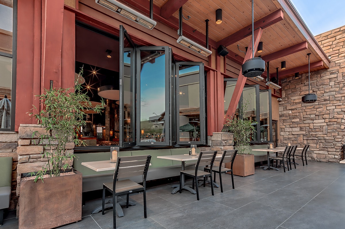 An outside view of semi-open bi-fold windows behind outdoor booth tables.