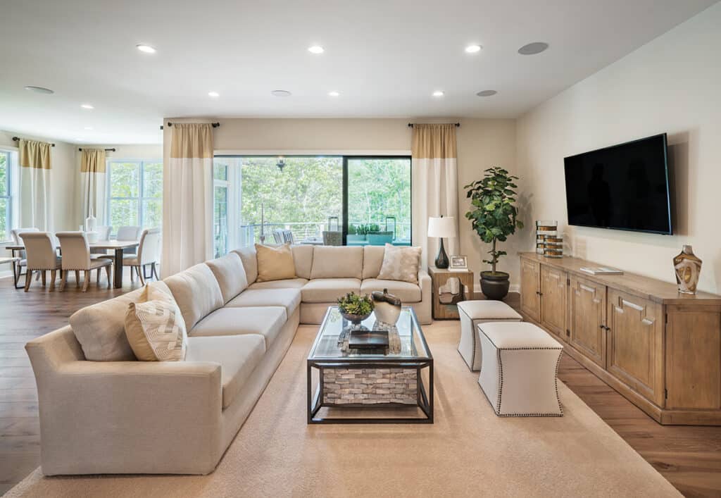 A large living space with an ivory couch and rug is expanded to the outdoors by a multi-slide glass door.