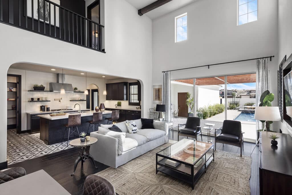 A living space with high ceilings is connected to an outdoor pool through a tall multi-slide glass door.