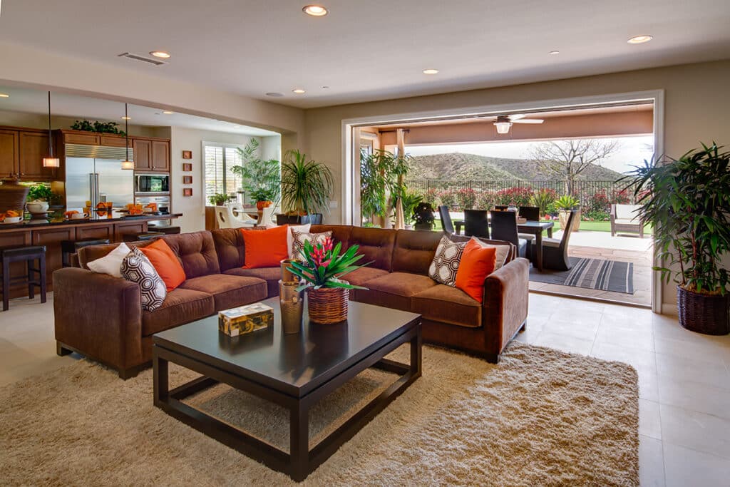 An outdoor dining area blends with an indoor kitchen and living room through a pocketed multi-slide glass door.