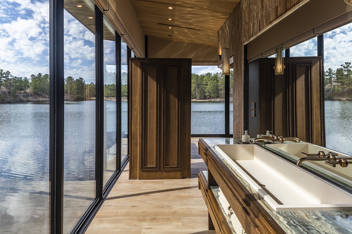 A bathroom vanity mirror reflects the lake visible through a glass wall.