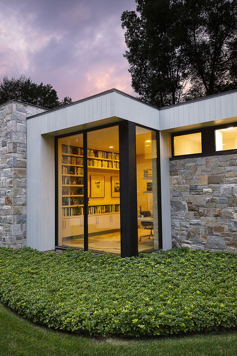 An artistic aesthetic is achieved through copious glass openings in every room, including this office full of bookshelves.