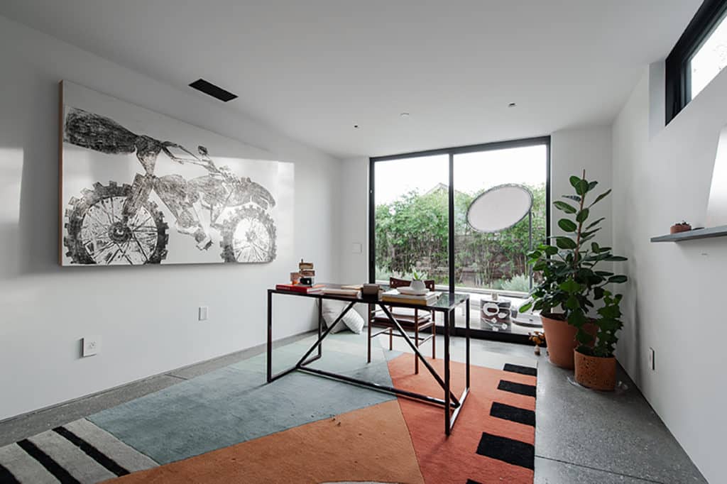 A wall-to-ceiling sliding patio door in the home office provide access to the outdoors.
