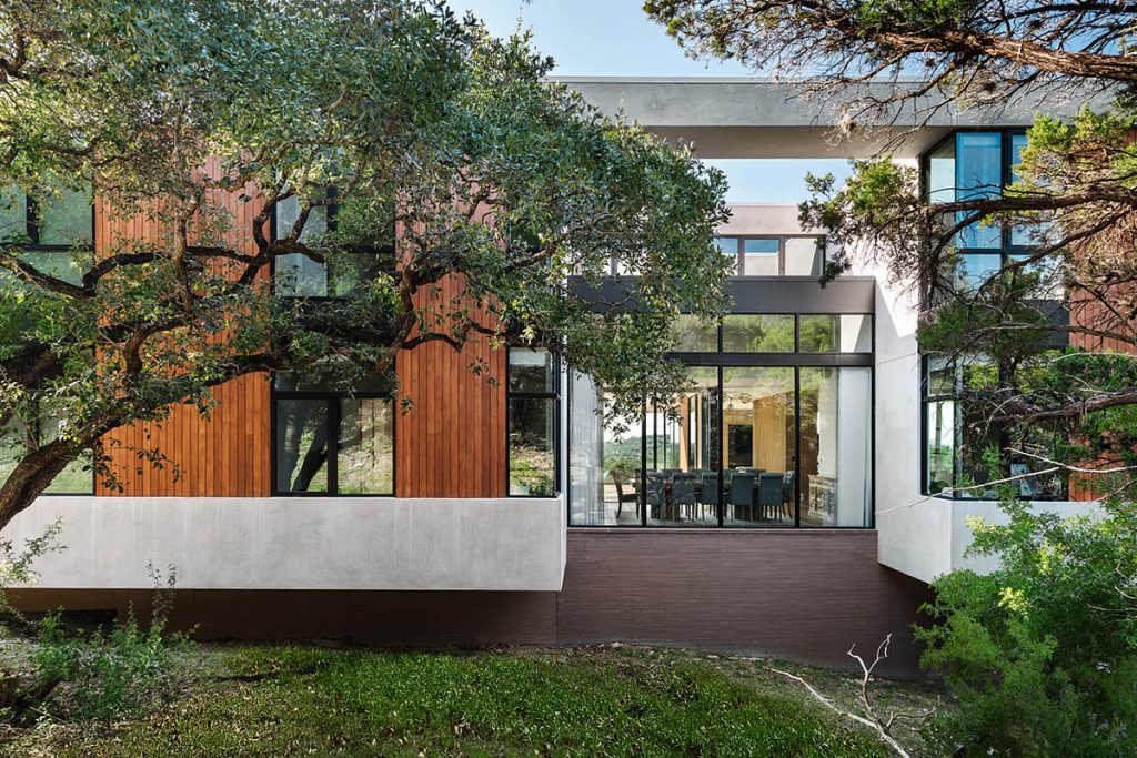 The dining room of the home features a Series 600 Window Wall with views to the surrounding wooded area.