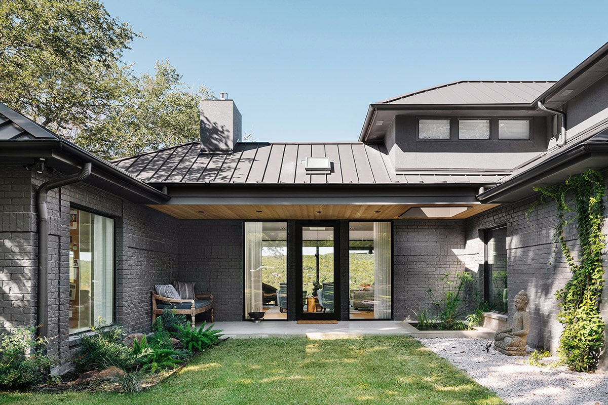 The entrance of the home has a meditative, Zen Garden-like vibe, enhanced by a hinged door and floor-to-ceiling glass.