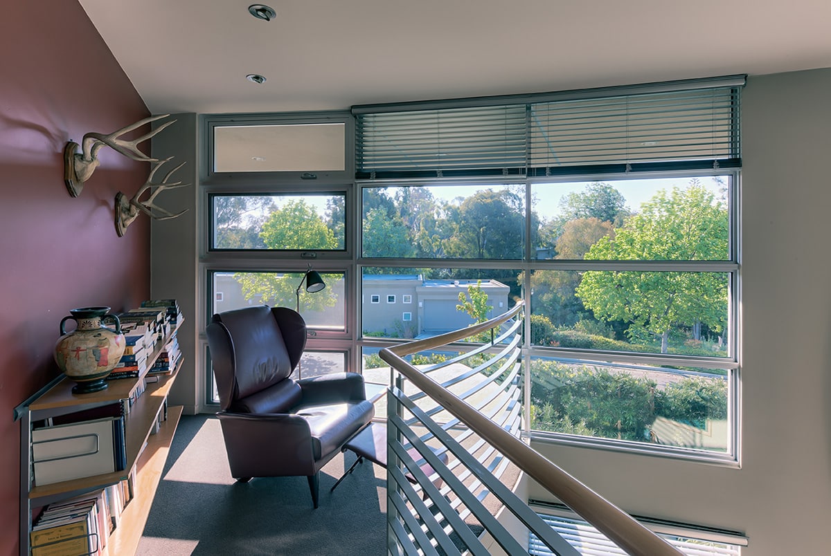 Natural light pours in through the second-story landing from fixed and casement windows filling the wall.
