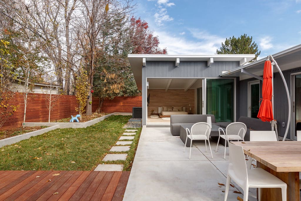 The master bedroom features a huge moving wall of glass, seamlessly blurring the boundaries between inside and the patio seating area outside.