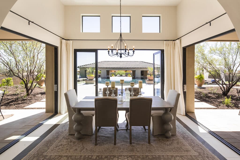 An indoor dining area is surrounded by giant moving walls of glass on three sides that lead outdoors.
