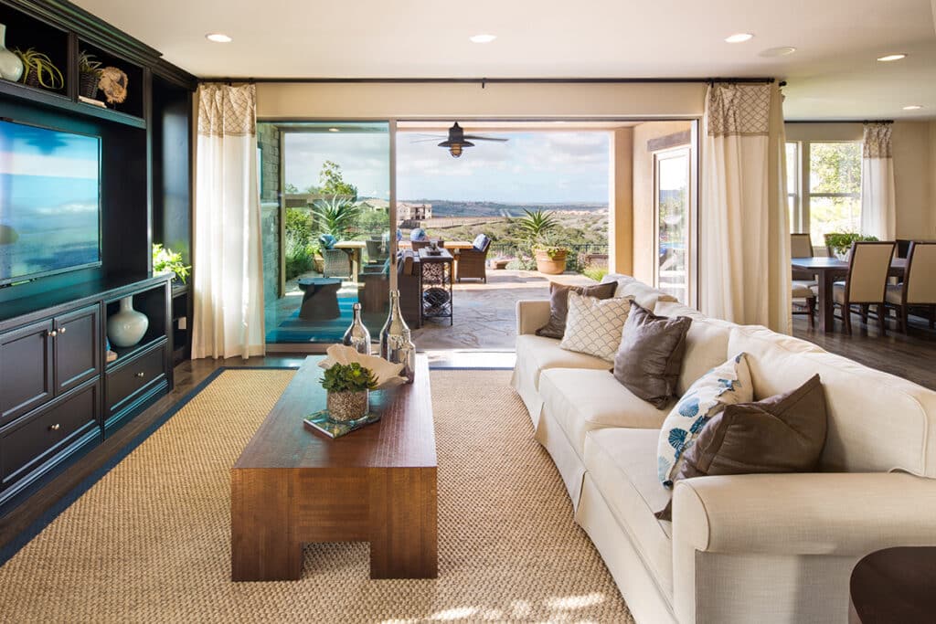 An indoor living room and outdoor California room is connected by floor to ceiling moving walls of glass.