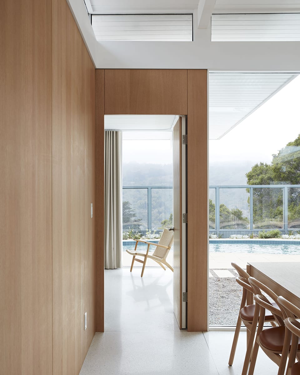Clerestory windows and a large wall of glass in front of the pool next to an open door.