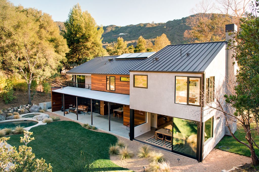A view of the white, glassy home with wood paneling accents from above.