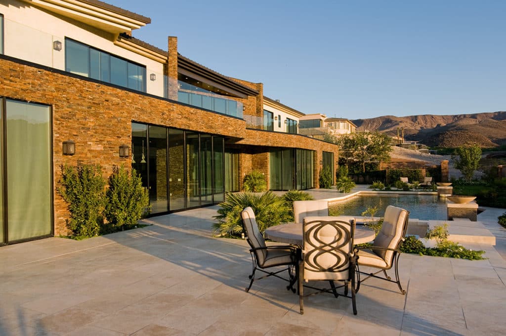 A back view of the home that blends with its surrounding through brown bricks and glazing.