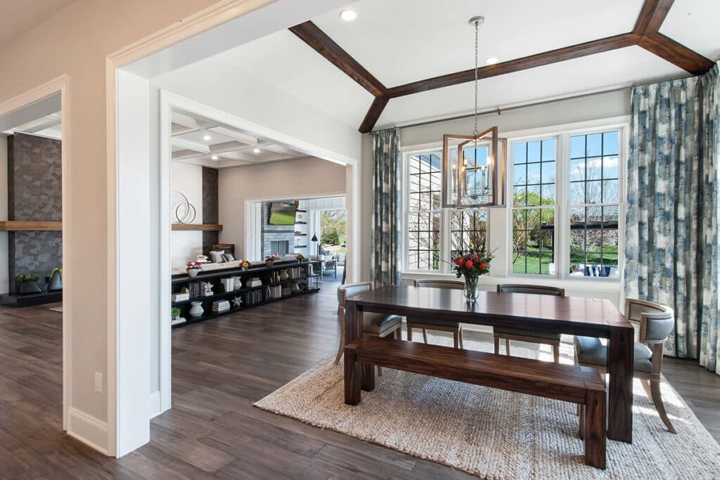 A cozy breakfast nook and indoor living space transitions to the outdoors through an open multi-slide glass door.