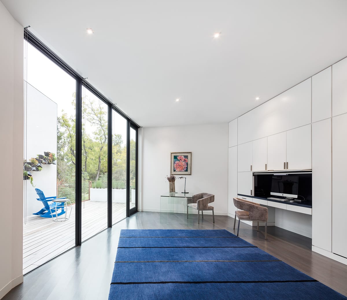 This floor-to-ceiling window wall and hinged door bathe the office in natural light.