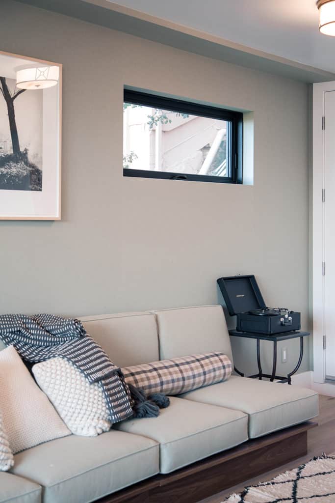 A horizontal awning window site above a white couch.