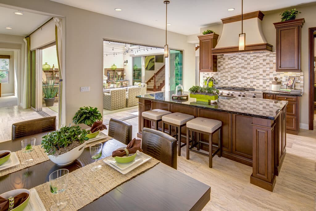 A kitchen opens to an outdoor courtyard through surrounding multi-slide glass doors.