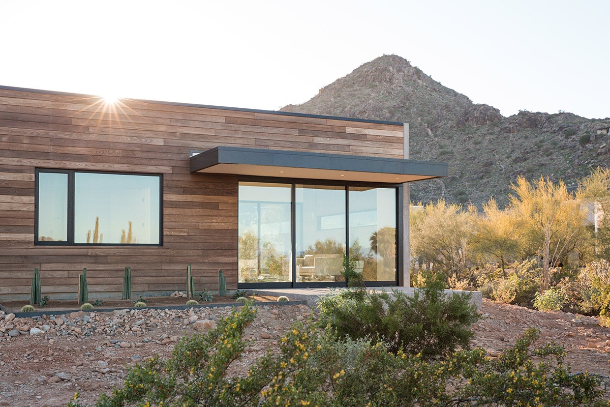 An outside view of one on the home’s multi-slide glass doors and windows with views of a mountain in the background.