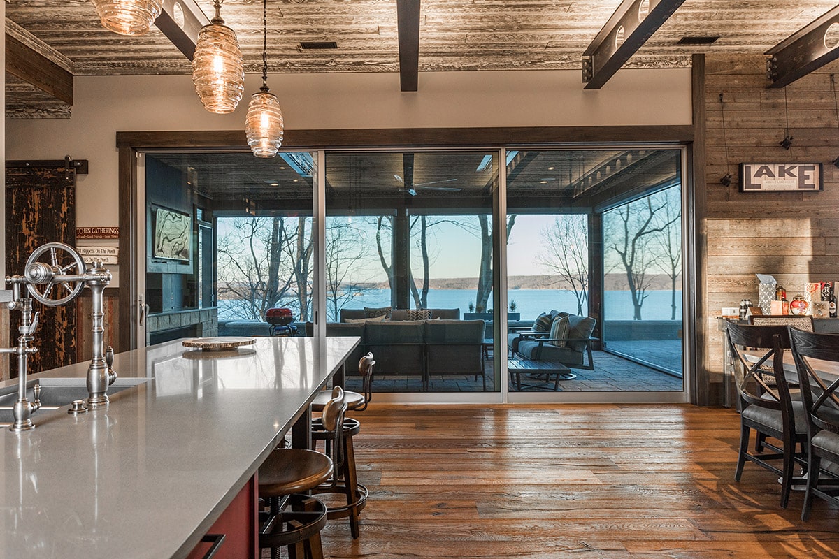 A massive multi-slide door opens from the kitchen and living area to a giant outdoor living space overlooking the lake.