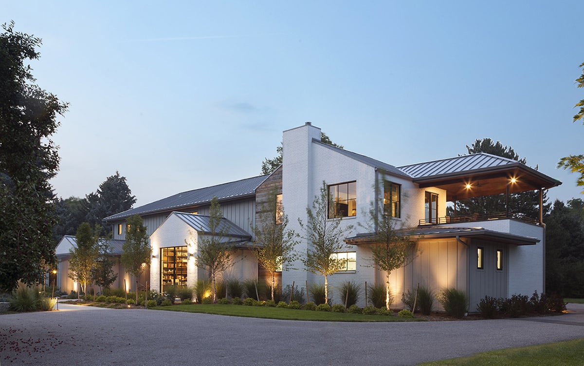The back profile of the Cape Cod-style home with two open multi-slide doors leading to the patio and a series of fixed windows on the second floor.