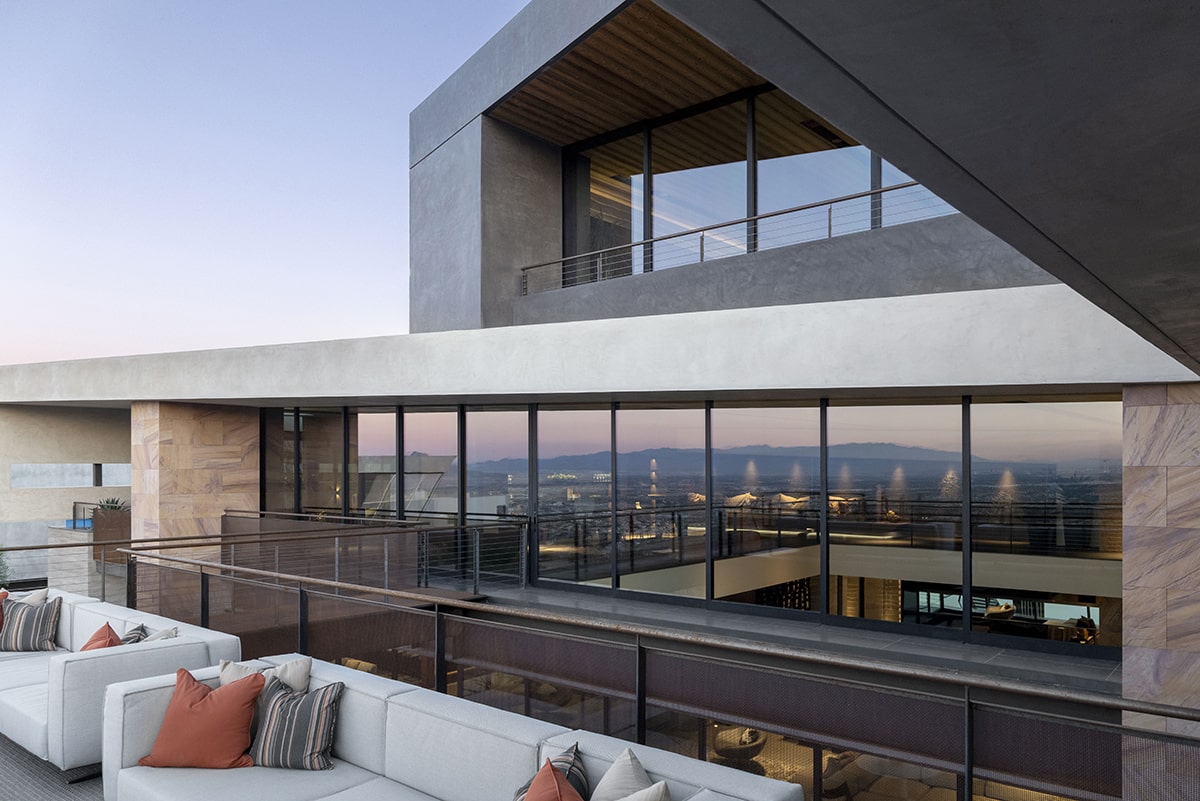 A large, wall-to-ceiling closed multi-slide door gives views of interior lighting and the second floor of the home.